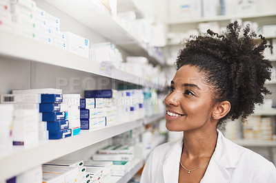 Buy stock photo Shot of a female pharmacist looking at the shelves in a chemist