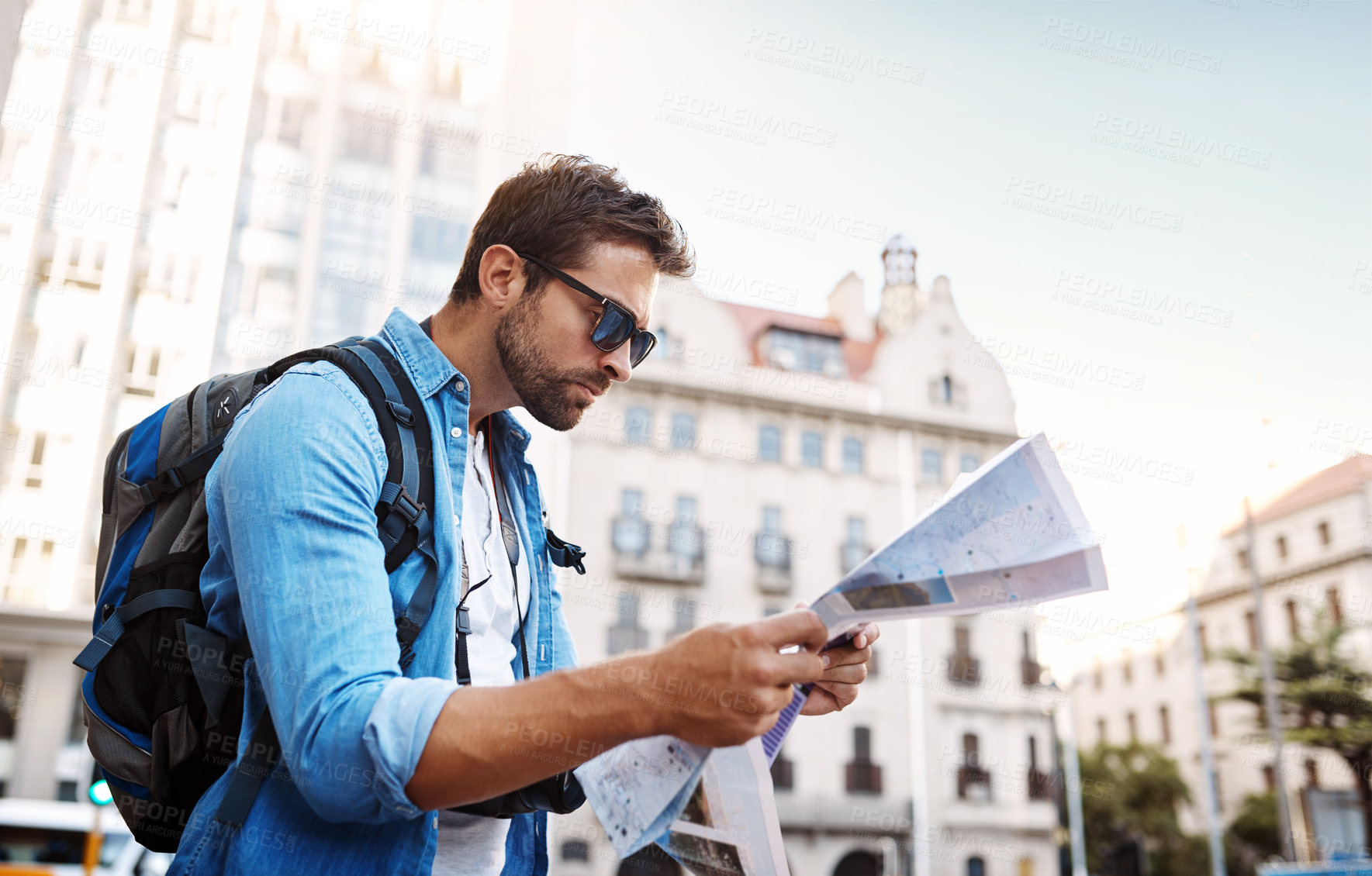 Buy stock photo Cropped shot of a handsome young man looking at a map while touring a foreign city