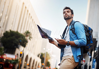 Buy stock photo Cropped shot of a handsome young man looking at a map while touring a foreign city