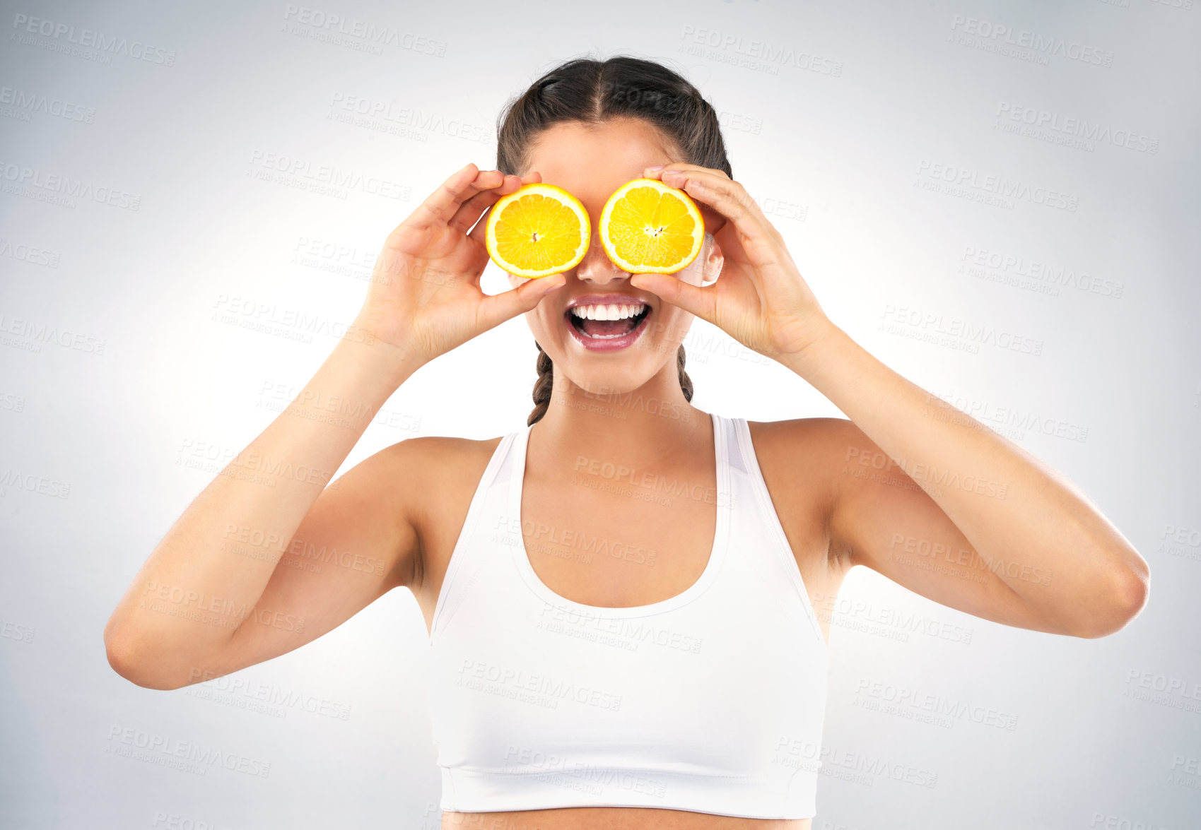 Buy stock photo Studio shot of a healthy young woman holding up oranges in front of her eyes against a grey background