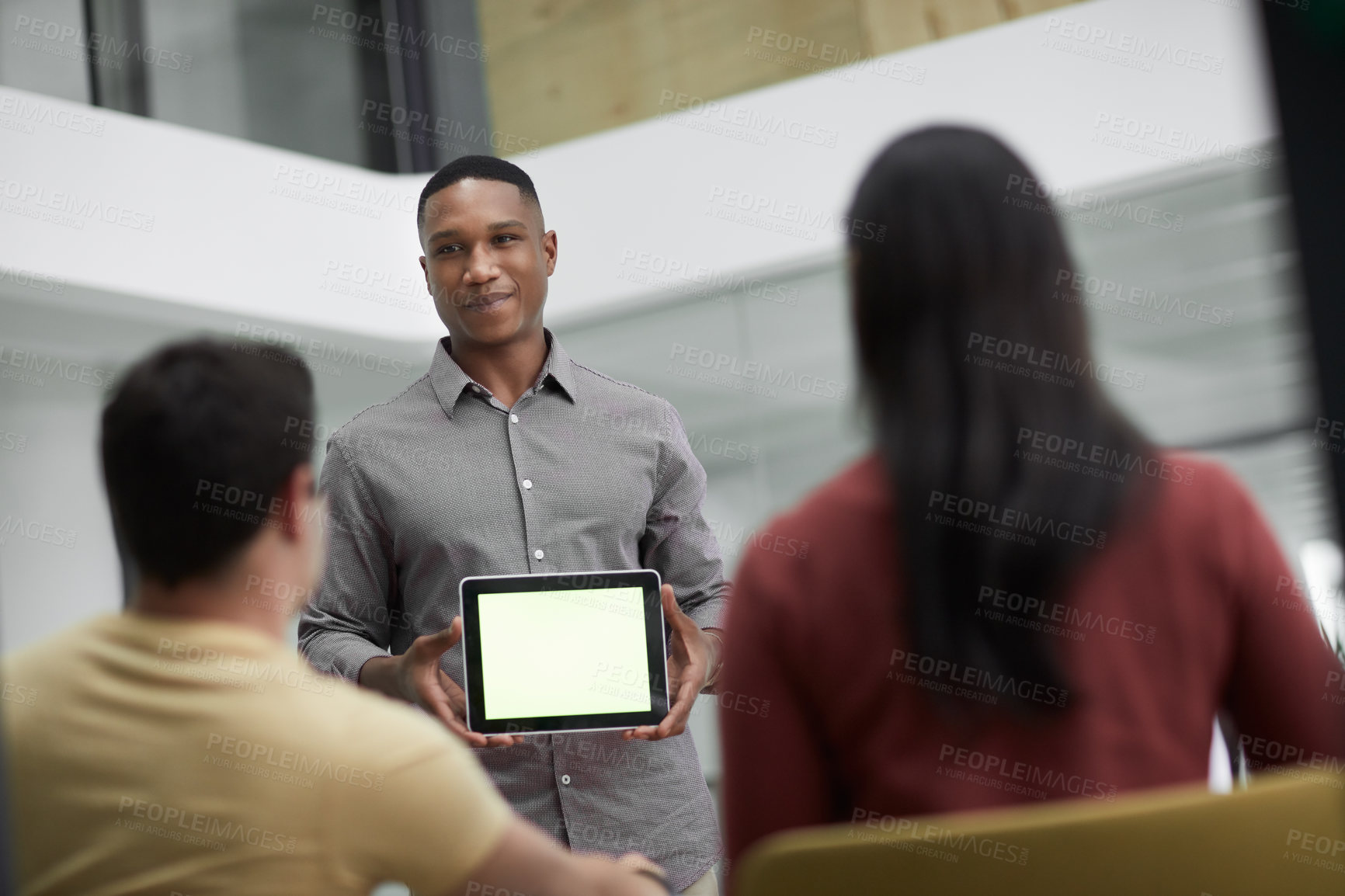 Buy stock photo Shot of a young businessman using a digital tablet during a meeting with colleagues in a modern office