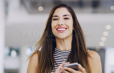 Buy stock photo Cropped shot of a young businesswoman using a smartphone while walking through a modern office