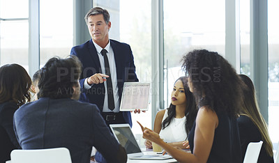 Buy stock photo Cropped shot of a businessman using a digital tablet while giving a presentation to his colleagues in an office