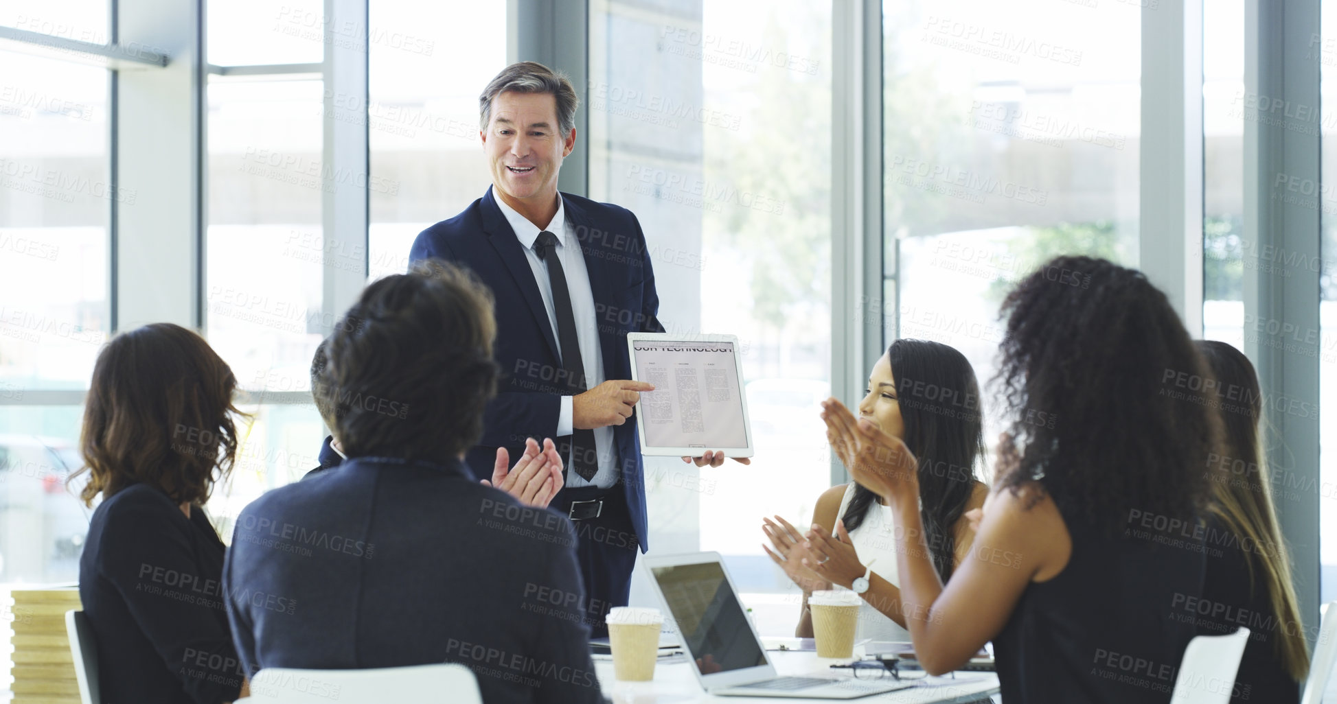 Buy stock photo Cropped shot of a businessman using a digital tablet while giving a presentation to his colleagues in an office