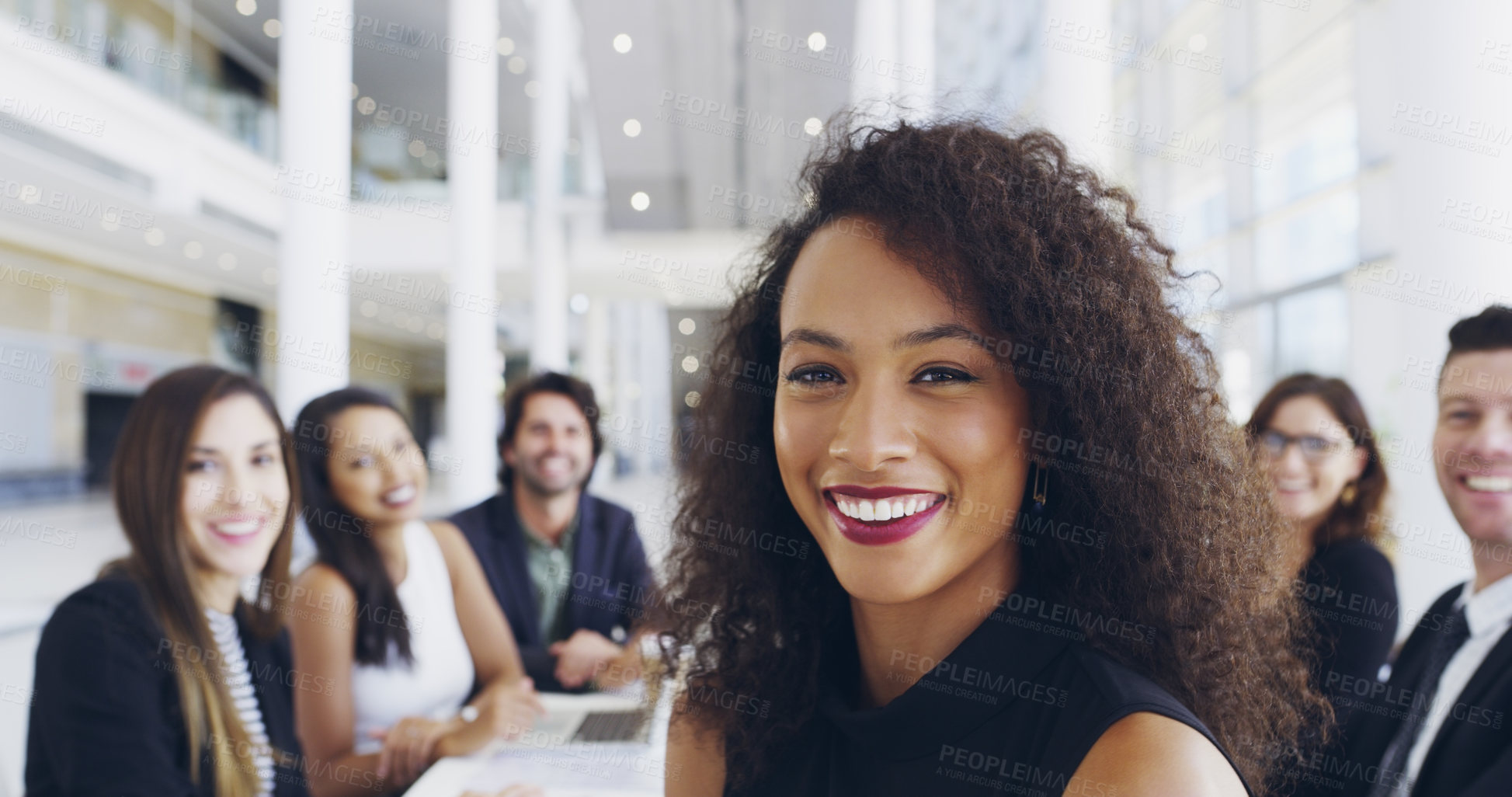 Buy stock photo Cropped shot of a young businesswoman smiling in an office during a meeting with her colleagues in the background