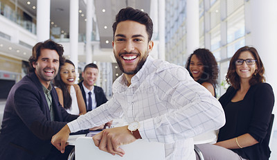 Buy stock photo Cropped shot of a young businessman smiling in an office during a meeting with his colleagues in the background