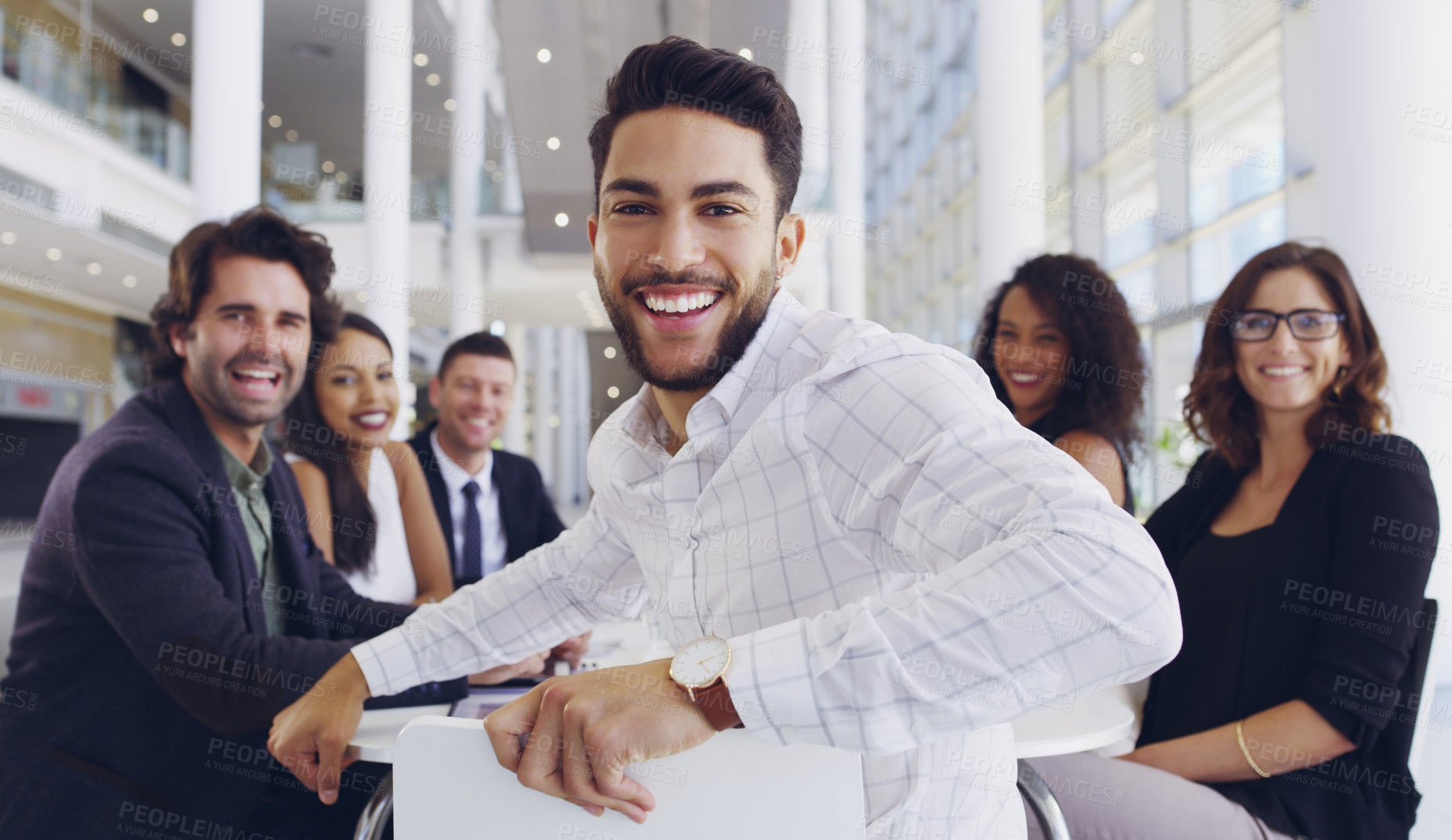 Buy stock photo Cropped shot of a young businessman smiling in an office during a meeting with his colleagues in the background
