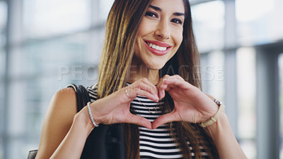 Buy stock photo Cropped shot of a young businesswoman showing a heart sign while walking through a modern office