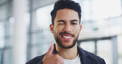 Buy stock photo Cropped shot of a young businessman showing winking and showing thumbs up while walking through a modern office