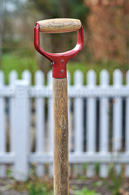 Buy stock photo Closeup of a handle of a shovel in a garden with a background of white picket fence with copyspace. Ready to be used for gardening or a lawn cleanup. Zoom in on wooden pattern of a gardening tool