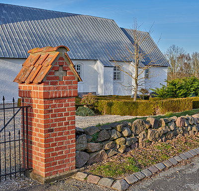 Buy stock photo Classic old white farm house or church with a beautiful green garden in the yard. Home built with traditional architecture with plants and trees on the porch. A residential building on a summer day