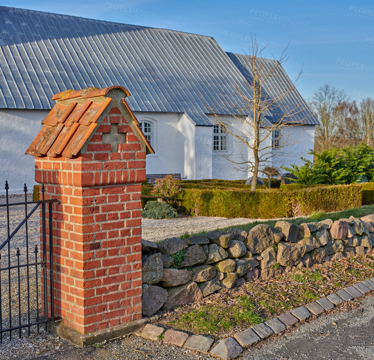 Buy stock photo Classic old white farm house or church with a beautiful green garden in the yard. Home built with traditional architecture with plants and trees on the porch. A residential building on a summer day