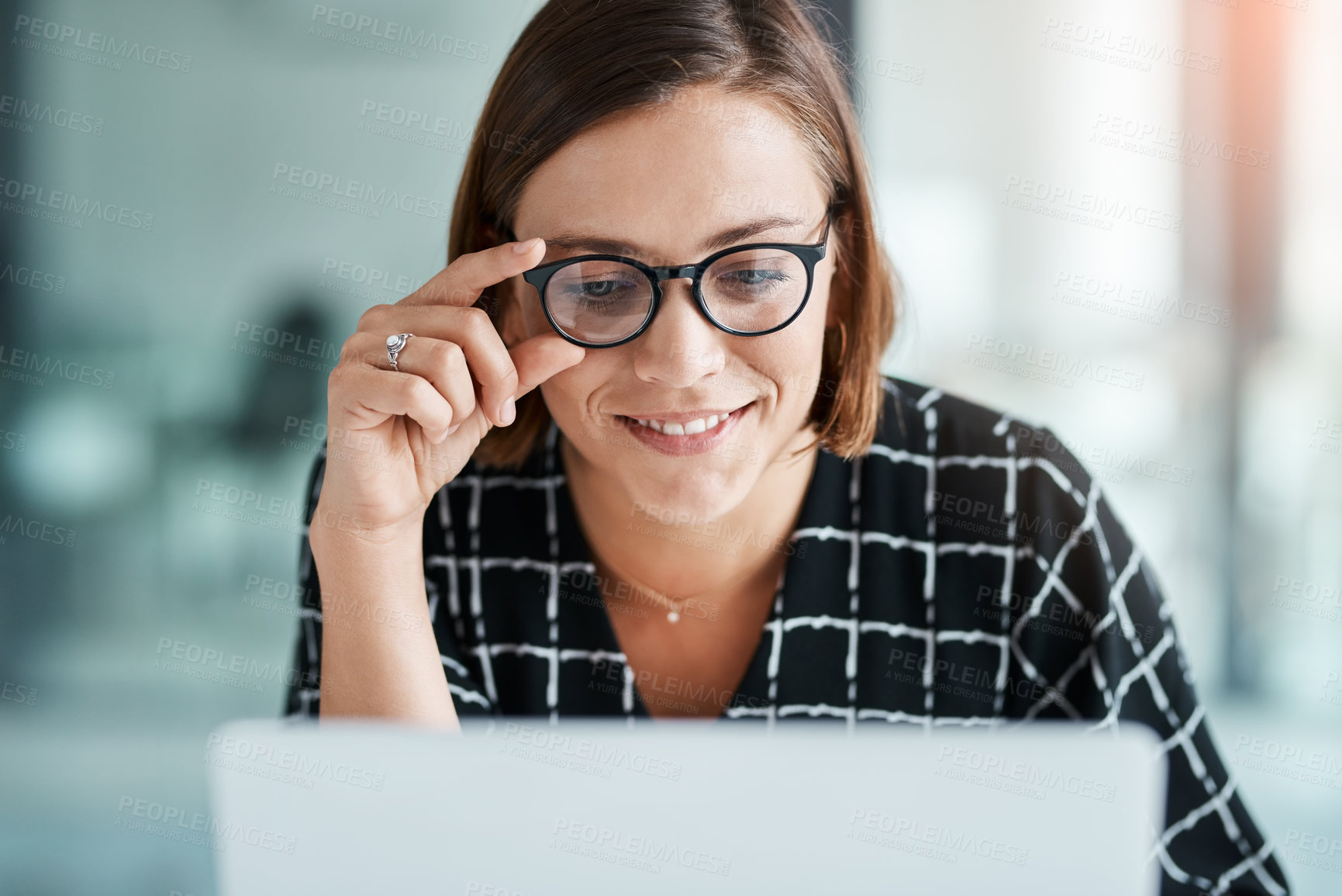 Buy stock photo Cropped shot of a happy young businesswoman working on a laptop in an office