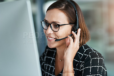 Buy stock photo Cropped shot of a happy young call centre agent working on a computer in an office