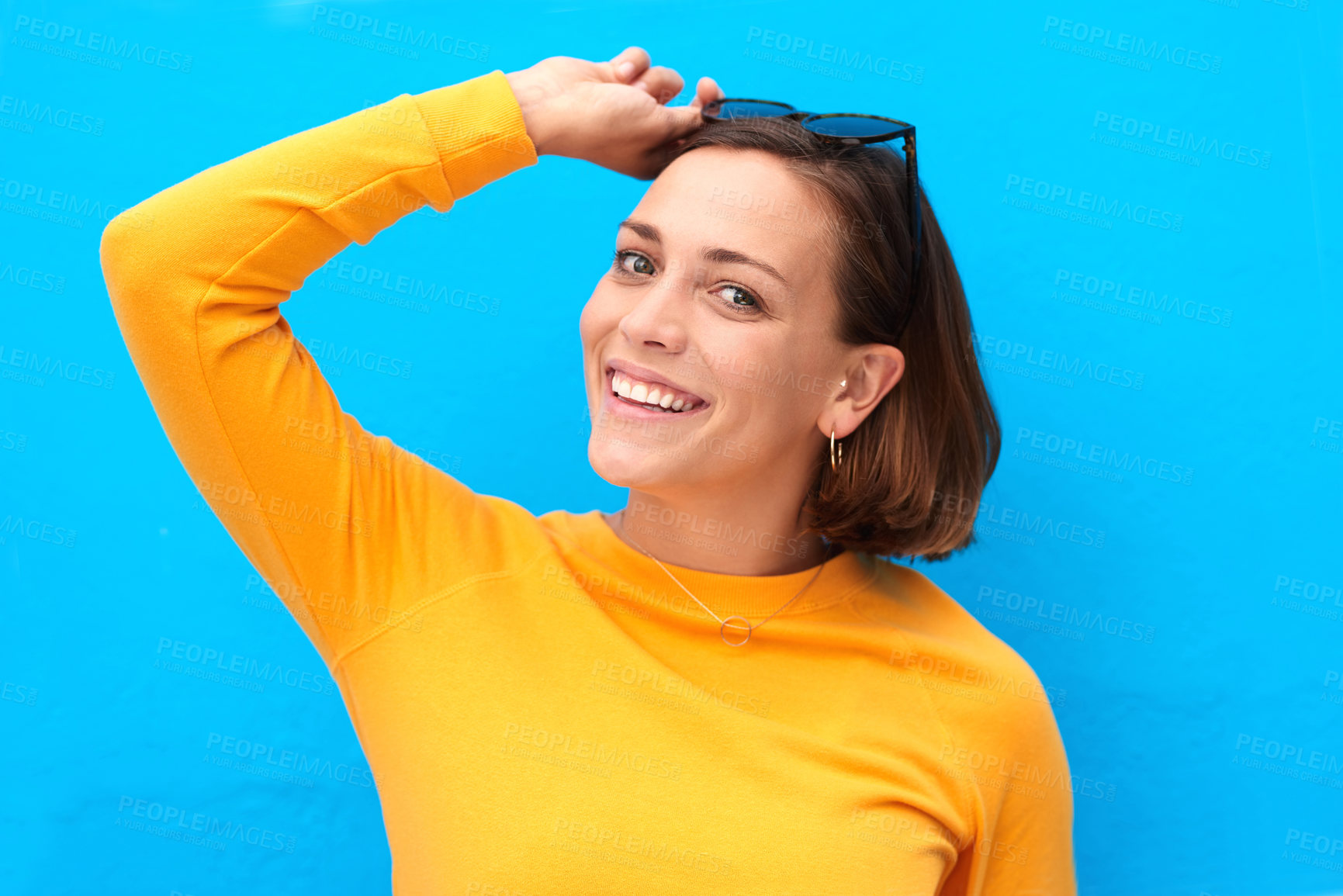 Buy stock photo Cropped portrait of a happy young woman posing against a blue background