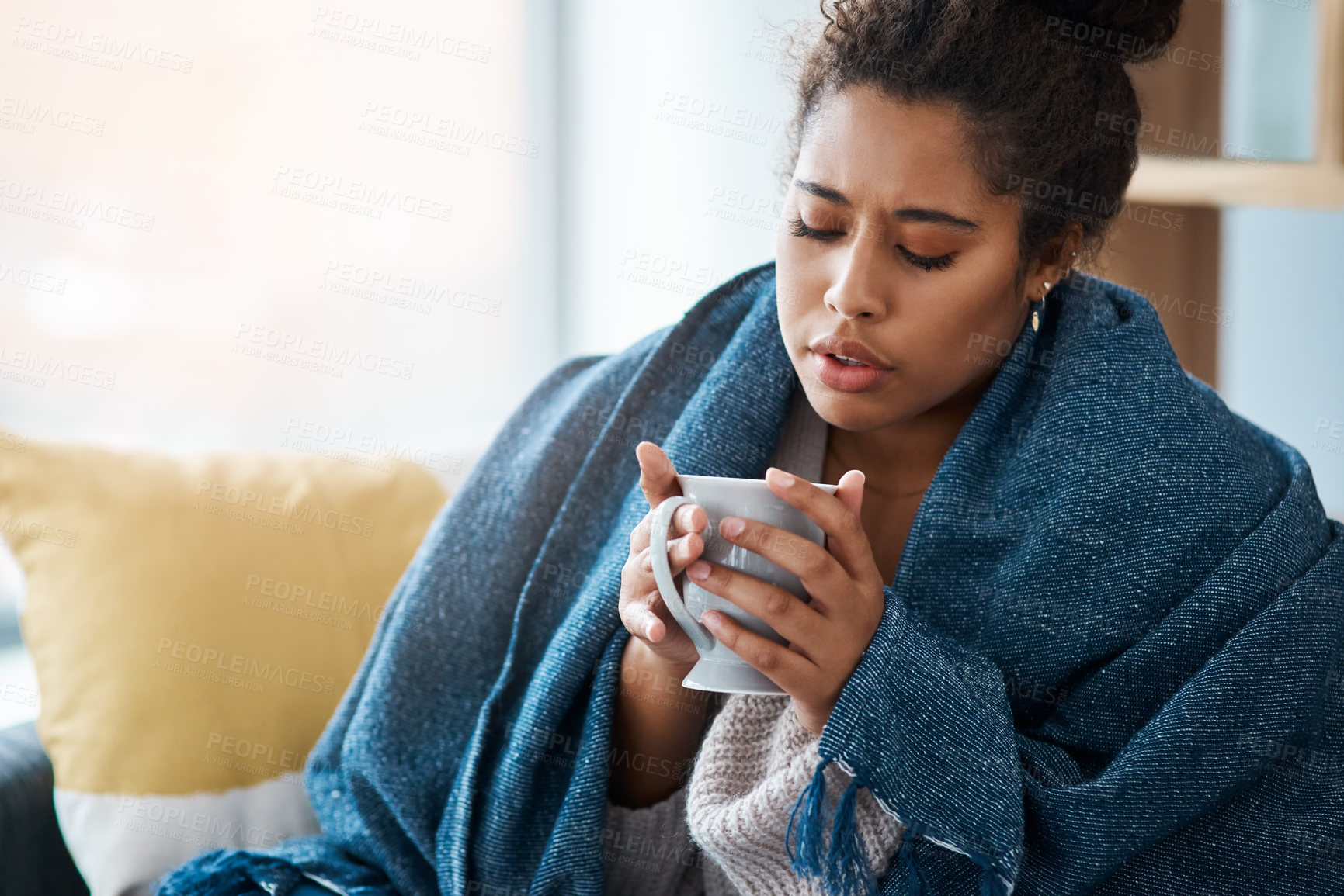 Buy stock photo Cropped shot of an attractive young woman covering herself with a blanket while having coffee at home