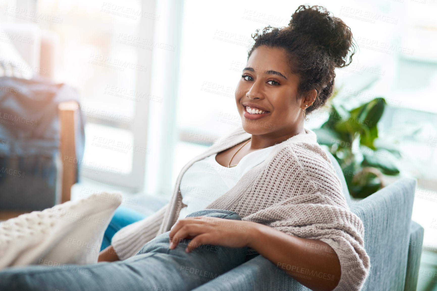 Buy stock photo Cropped portrait of a happy young woman relaxing on her couch at home