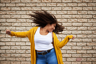 Buy stock photo Cropped shot of a happy young woman dancing against a brick wall
