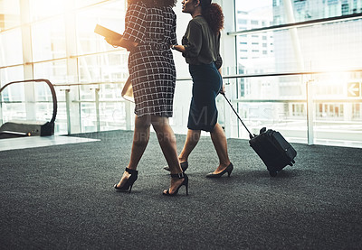 Buy stock photo Cropped shot of two unrecognizable businesswomen walking together with their bags in a modern workplace