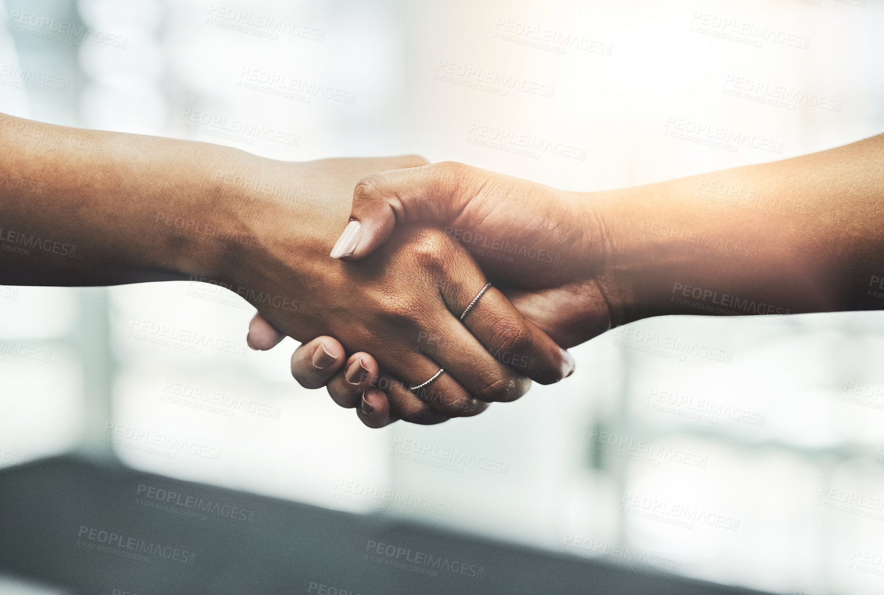 Buy stock photo Closeup shot of two unrecognizable businesswomen shaking hands while standing in a modern workplace