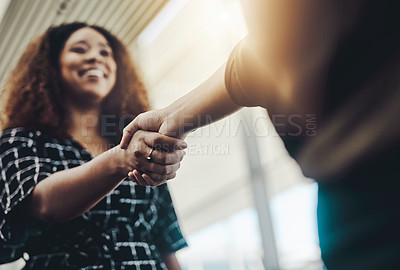 Buy stock photo Low angle shot of an attractive young businesswoman shaking hands with an associate in a modern workplace