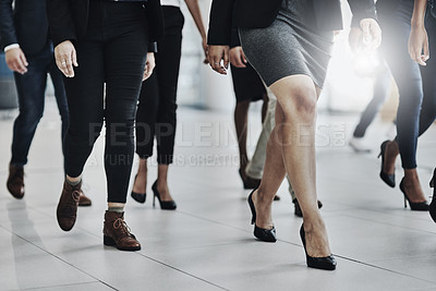 Buy stock photo Low angle shot of a group of unrecognizable businesspeople walking together inside of the office at work during the day