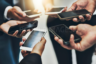 Buy stock photo Cropped shot of a group of unrecognizable businesspeople texting on their phones at work