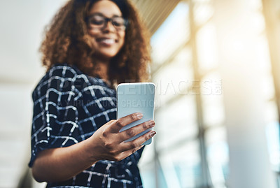 Buy stock photo Low angle shot of an unrecognizable businesswoman using a smartphone while standing in a modern office