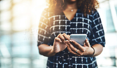 Buy stock photo Low angle shot of an unrecognizable businesswoman using a smartphone while standing in a modern office