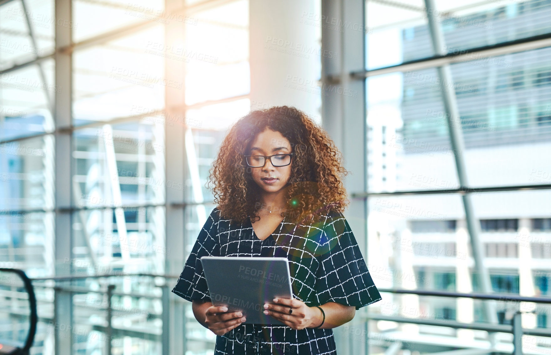 Buy stock photo Cropped shot of an attractive young businesswoman using a digital tablet while standing in a modern office