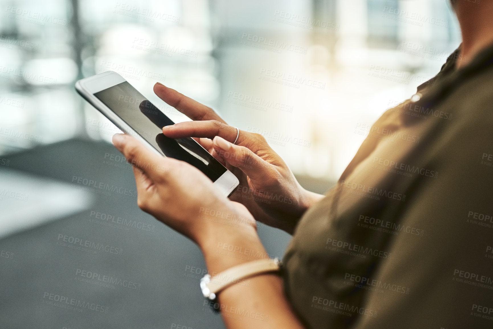 Buy stock photo Cropped shot of an unrecognizable businesswoman using a smartphone while standing in a modern office