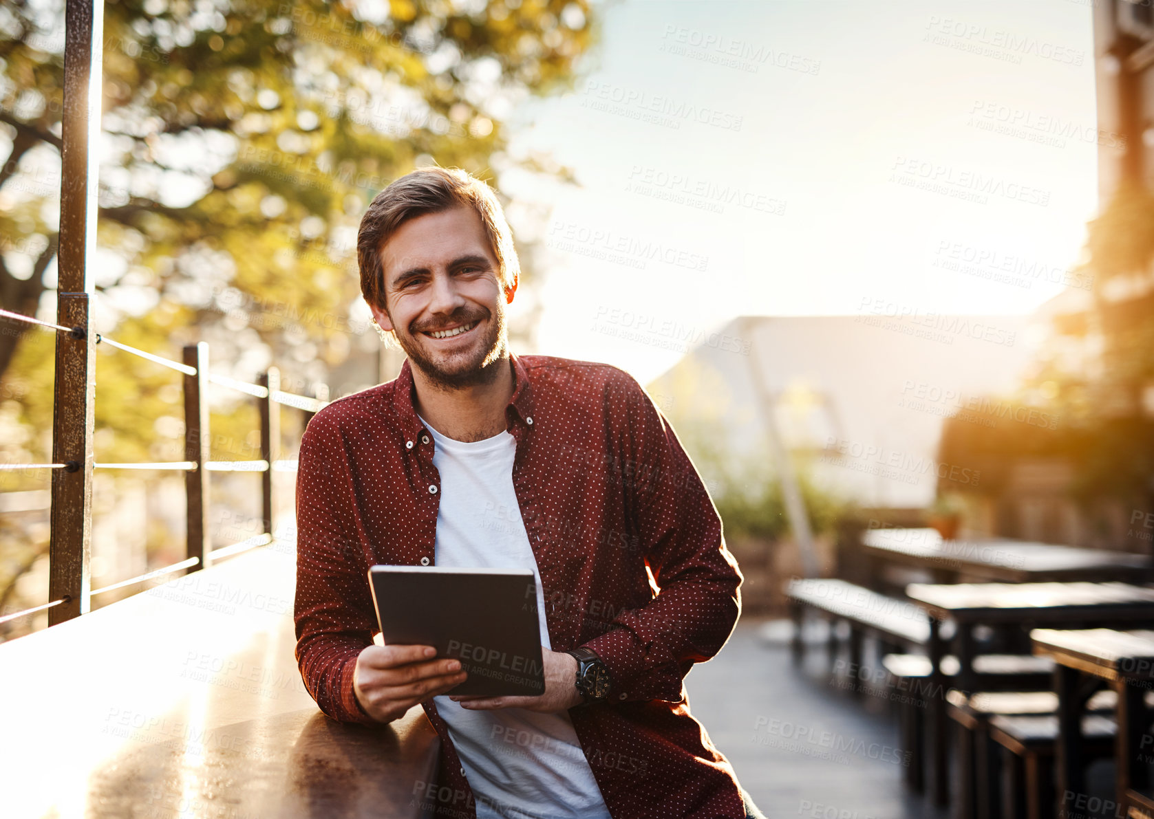 Buy stock photo Cropped portrait of a handsome young man using his digital tablet outside