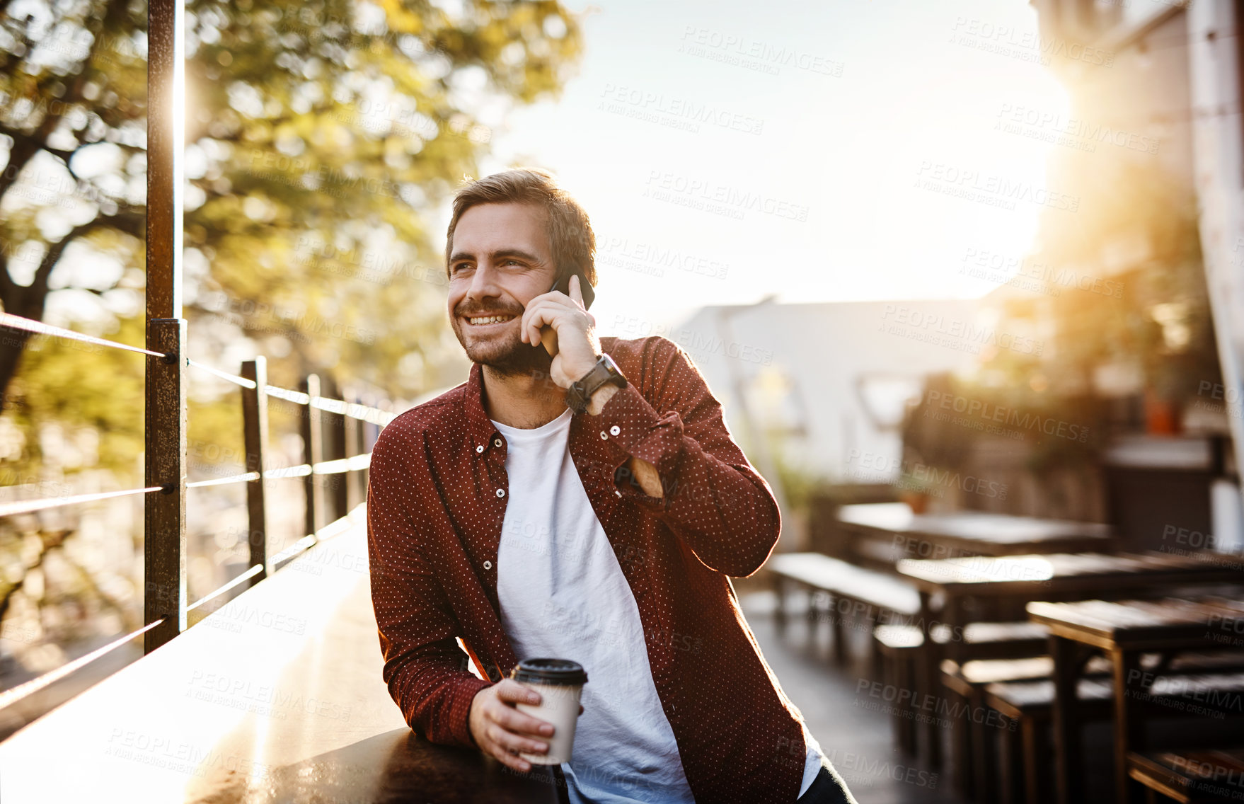 Buy stock photo Cropped shot of a handsome young man talking on his cellphone while drinking a coffee outside