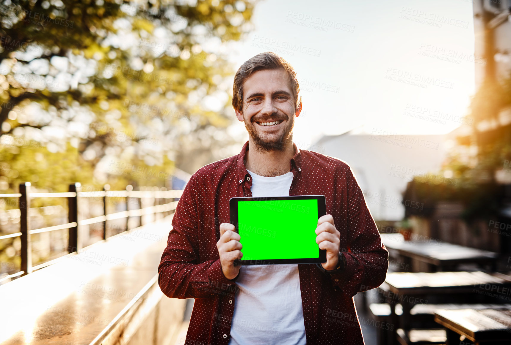 Buy stock photo Cropped portrait of a handsome young man showing you green screen on his digital tablet outside