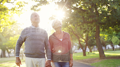 Buy stock photo Senior couple, holding hands and walking outdoor at a park with love, care and support. A elderly man and woman in nature for a walk, quality time and hope for a healthy marriage or retirement