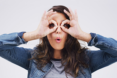 Buy stock photo Portrait, funny face and finger glasses with a woman in studio on a gray background looking silly or goofy. Comedy, comic and playing with a crazy young female person joking indoor for fun or humor
