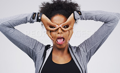 Buy stock photo Portrait, funny face and finger glasses with an african woman in studio on a gray background looking silly or goofy. Comedy, comic and mask with a crazy young female person joking for fun or humor