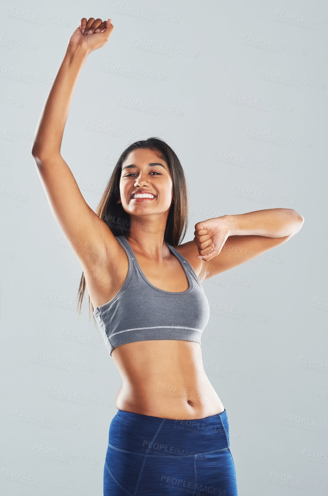 Buy stock photo Cropped studio portrait of an attractive young woman cheering with arms raised against a gray background