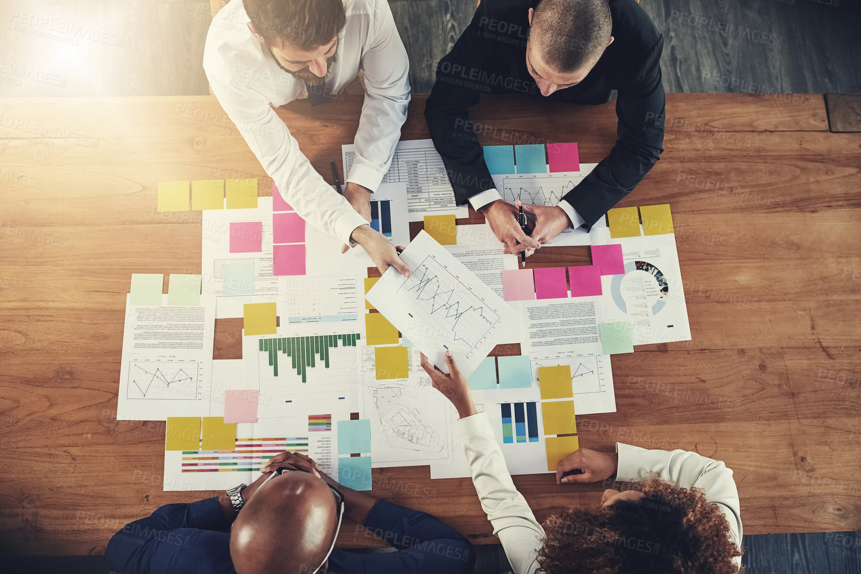 Buy stock photo High angle shot of a group of businesspeople going over paperwork during a meeting in their office