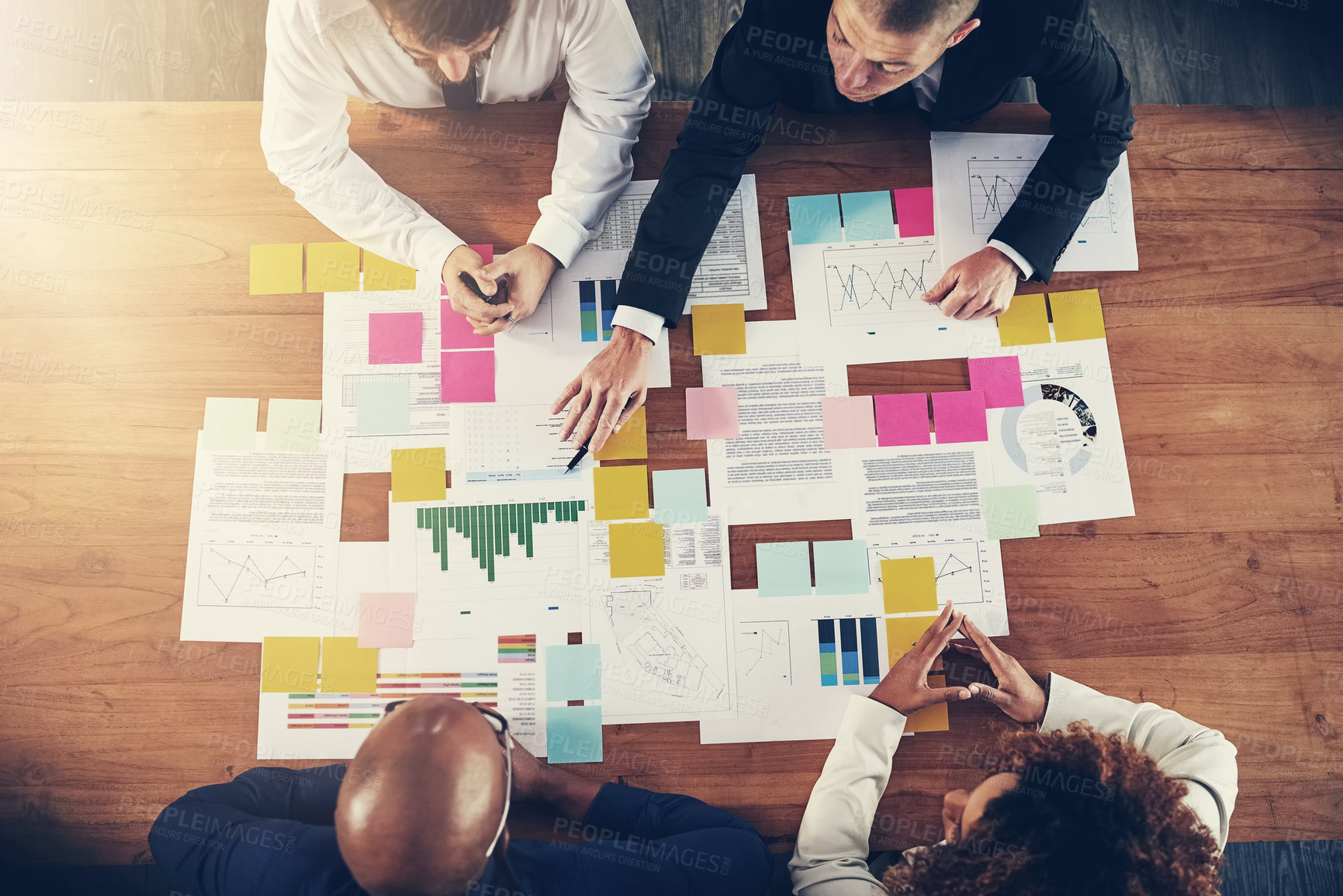 Buy stock photo High angle shot of a group of businesspeople going over paperwork during a meeting in their office