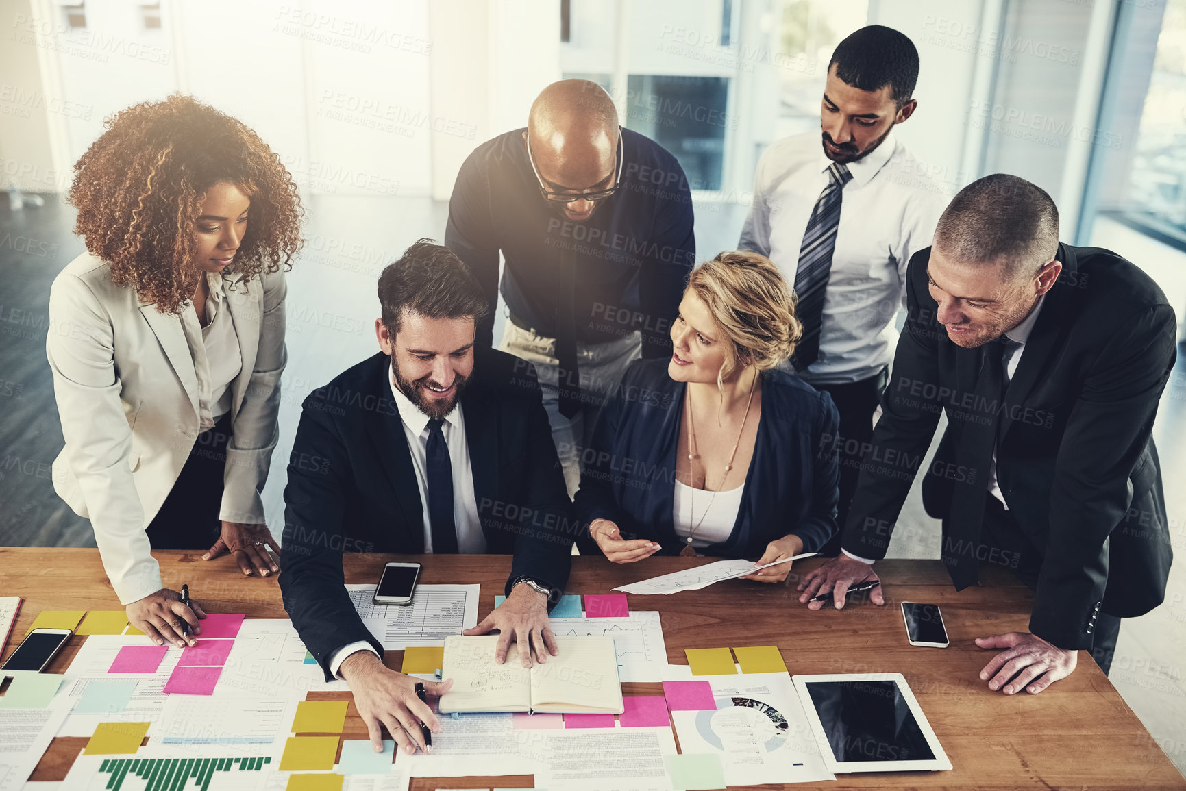 Buy stock photo Cropped shot of a group of businesspeople going over paperwork during a meeting in their office