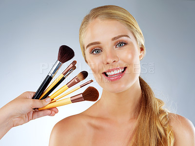 Buy stock photo Woman, portrait and makeup brushes or choice in studio, transformation and options on blue background. Female person, skincare and cosmetic tools or collection, facial treatment and dermatology