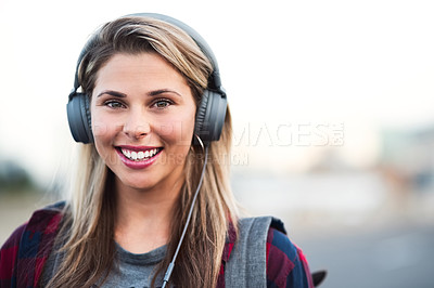 Buy stock photo Portrait of an attractive young woman wearing headphones while walking through the city