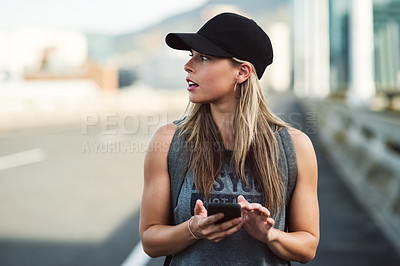 Buy stock photo Shot of an attractive young woman using her cellphone while walking around in the city