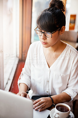 Buy stock photo Shot of a beautiful young woman drinking coffee at a cafe while getting some work done