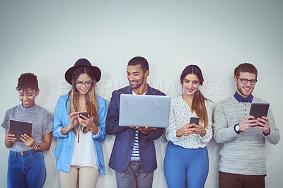 Buy stock photo Studio shot of a group of young businesspeople using wireless technology while standing in line against a grey background