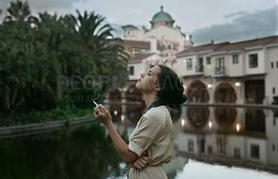 Buy stock photo Cropped shot of an attractive young woman smoking a cigarette next to a lake in an urban setting
