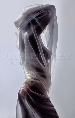 Buy stock photo Shot of an attractive young woman covered in sheer fabric posing against a grey background