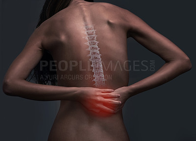 Buy stock photo Rearview shot of a woman  suffering from back pain against a dark background