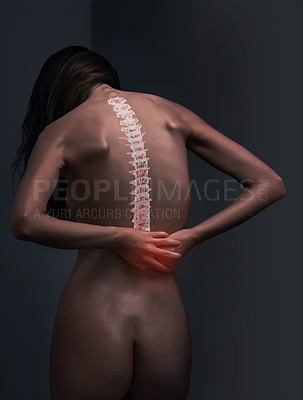 Buy stock photo Rearview shot of a naked young woman suffering from lower back pain against a dark background